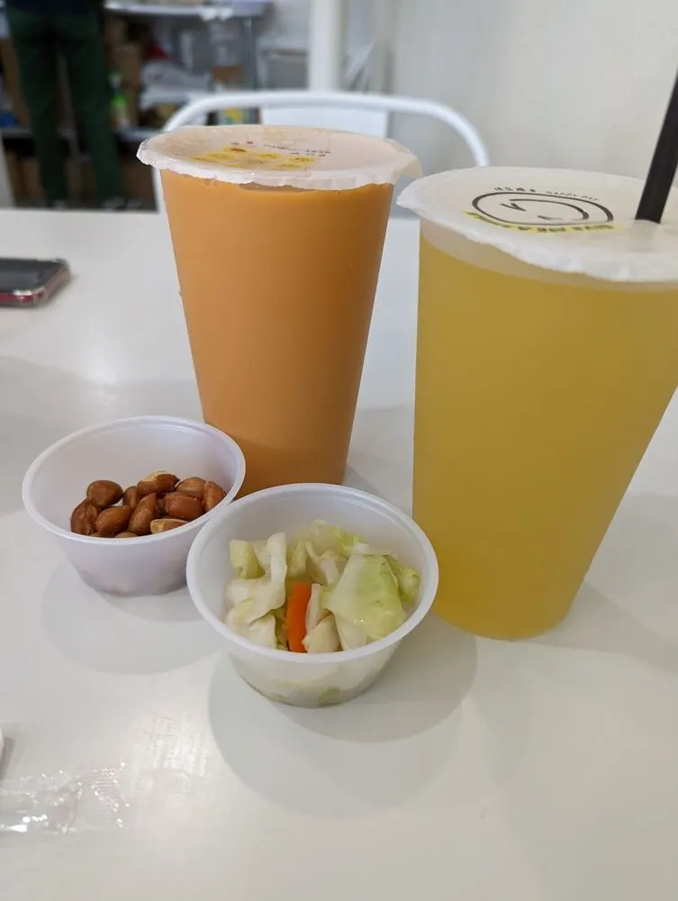 Taiwanese milk tea and kumquat green tea with small cups of peanuts and pickled cabbage on a table at Ooodles